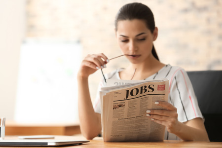 Young businesswoman reading newspaper in officeの写真素材