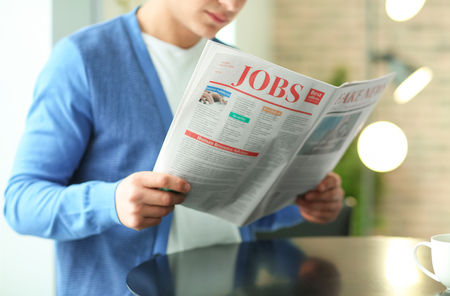 Handsome young man reading newspaper in cafeの写真素材