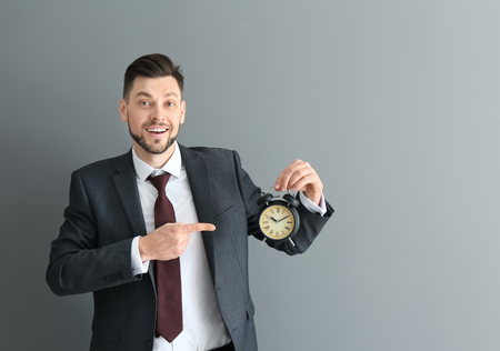 Businessman with alarm clock on gray background. Time management conceptの写真素材