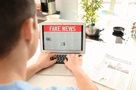 Young man reading news on laptop screen indoorsの写真素材