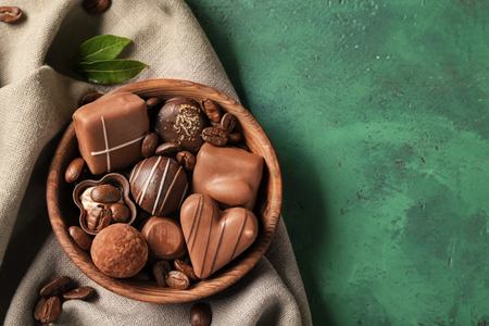 Bowl with different tasty chocolate candies on textured tableの写真素材