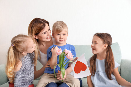 Mother receiving gifts from her cute little children at homeの写真素材