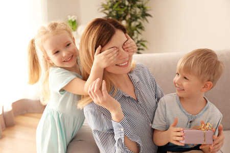 Cute little children greeting their mother at home