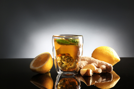 Glass of tea with ginger and lemon on dark backgroundの写真素材