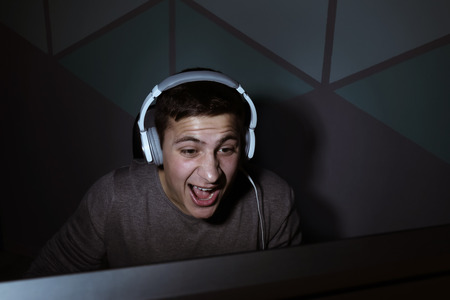 Young man playing video games at home in darknessの写真素材