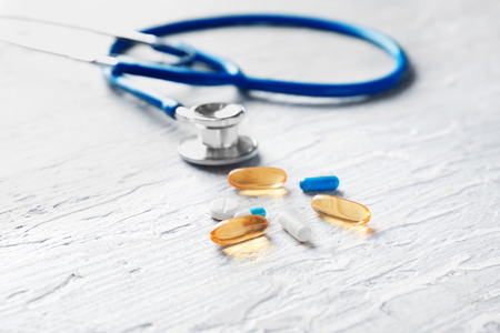 Pills with stethoscope on wooden background. Health care conceptの写真素材