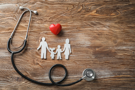 Family figure, red heart and stethoscope on wooden background. Health care conceptの写真素材