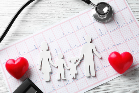 Stethoscope, family figure and cardiogram on wooden background. Health care conceptの写真素材
