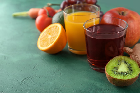 Fresh fruits and vegetables with glasses of juice on color background. Healthy food conceptの写真素材