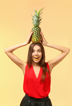 Attractive young woman with pineapple on color backgroundの写真素材