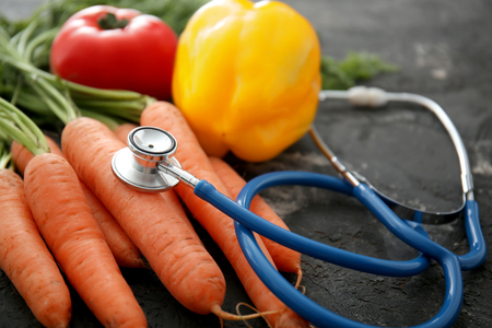 Stethoscope with vegetables on dark grey background. Healthy food conceptの写真素材