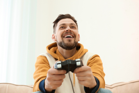 Emotional man playing video game at homeの写真素材