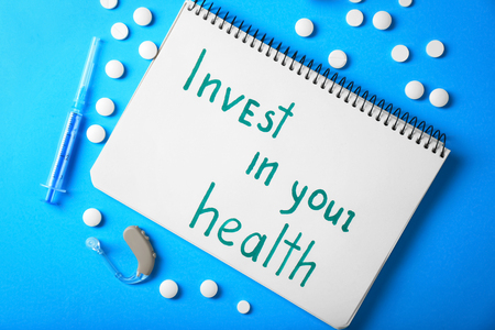 Phrase "Invest in your health" written in notebook on color backgroundの写真素材