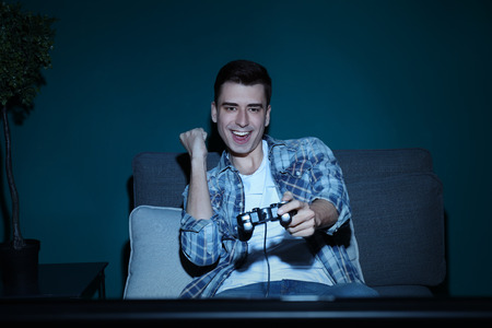 Young man playing video game at home in the eveningの写真素材