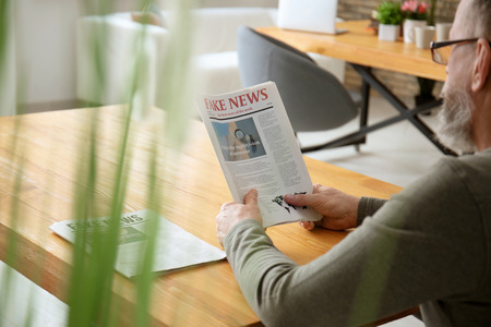 Senior man reading newspaper in cafeの写真素材