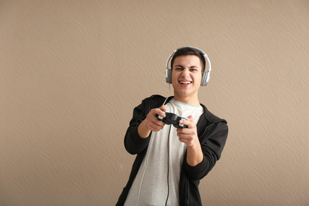 Young man with gamepad on color backgroundの写真素材