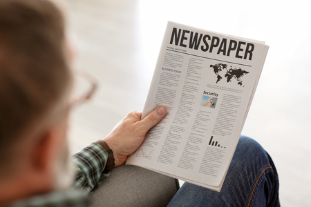 Senior man reading newspaper at homeの写真素材