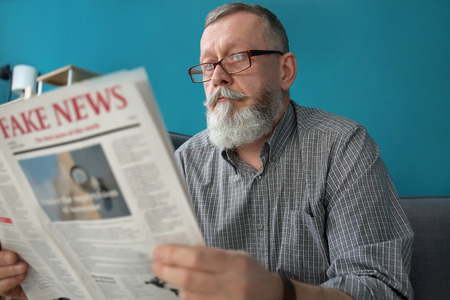 Senior man reading newspaper at home
