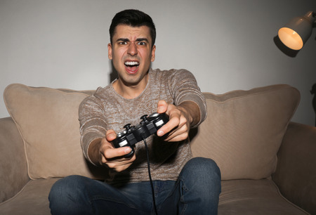 Young man playing video game at home in the evening