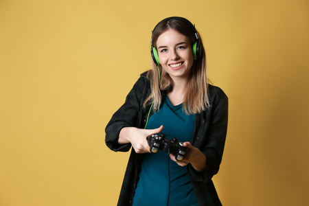 Young woman with gamepad on color backgroundの写真素材
