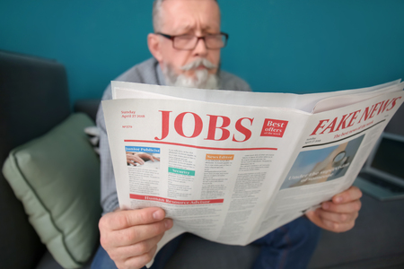 Senior man reading newspaper at homeの写真素材