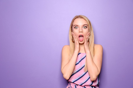 Surprised young woman on color backgroundの写真素材