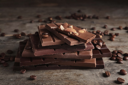 Chocolate bars with almonds and coffee beans on wooden backgroundの写真素材