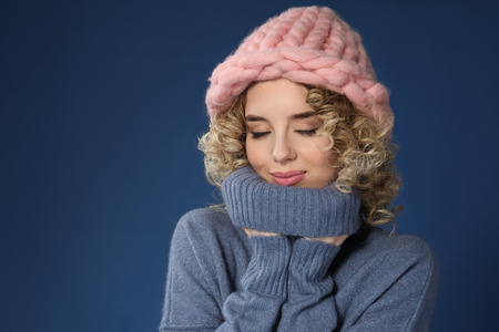 Portrait of beautiful young woman in warm clothes on color background