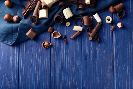 Chocolate curls with hazelnuts on color wooden backgroundの写真素材