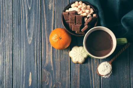 Cup of hot chocolate, sweets and mandarin on wooden tableの写真素材