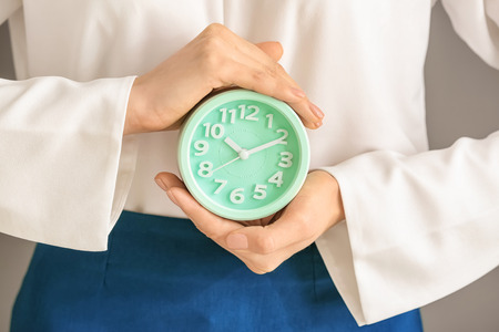 Woman holding alarm clock, closeup. Time management concept