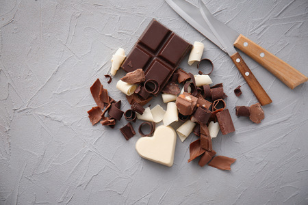 Pieces of chocolate with curls on light background