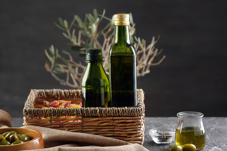 Wicker basket with bottles of olive oil on tableの写真素材
