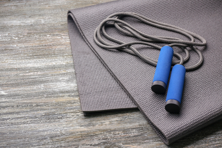 Yoga mat and jump rope on wooden backgroundの写真素材