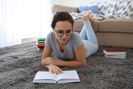 Young woman reading book on floor at home