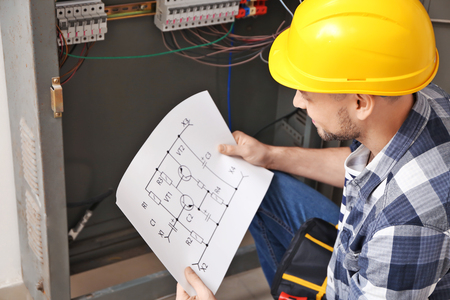 Electrician with circuit diagram near distribution boardの写真素材