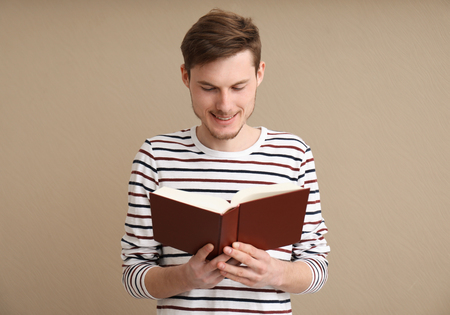 Young man reading book on color backgroundの写真素材