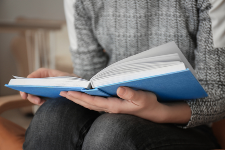 Young woman reading book at home, closeupの写真素材