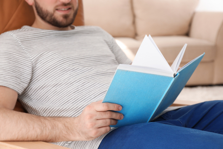 Young man reading book at homeの写真素材