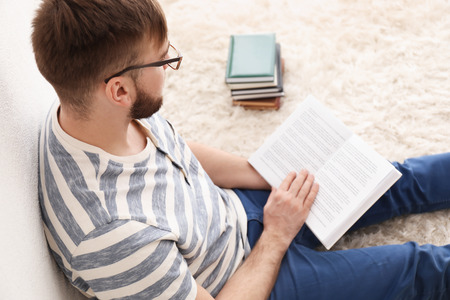 Young man reading books at homeの写真素材