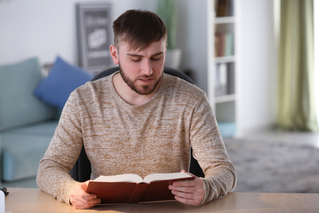 Young man reading book at homeの写真素材