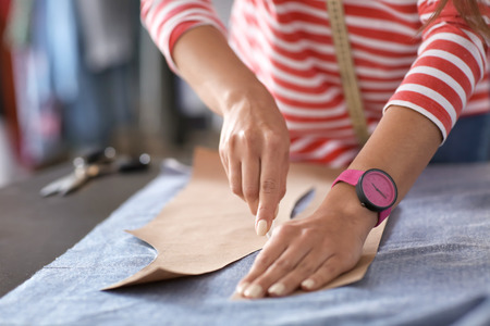 Young female tailor working with sewing pattern in atelier