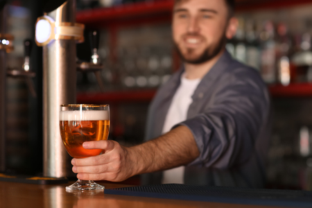 Bartender with glass of beer in barの写真素材