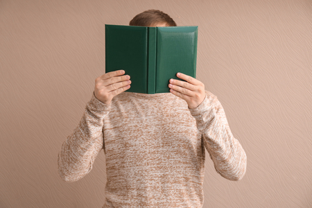Young man with book on color backgroundの写真素材