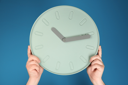 Male hands with clock on color background. Time management conceptの写真素材