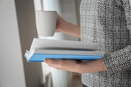Young woman reading book at home, closeup