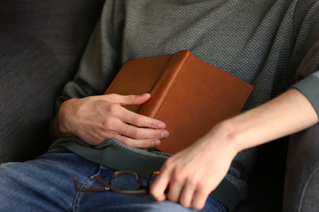Young man with book sleeping in armchair at home, closeup
