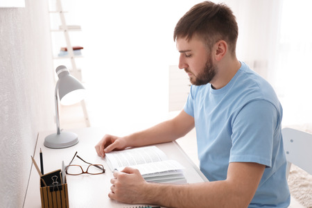 Young man reading book at homeの写真素材