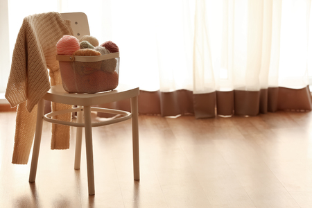 Basket with knitting threads on chair indoorsの写真素材