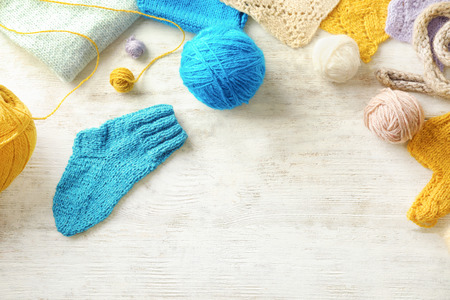 Composition with knitting yarn and clothes on table, top view